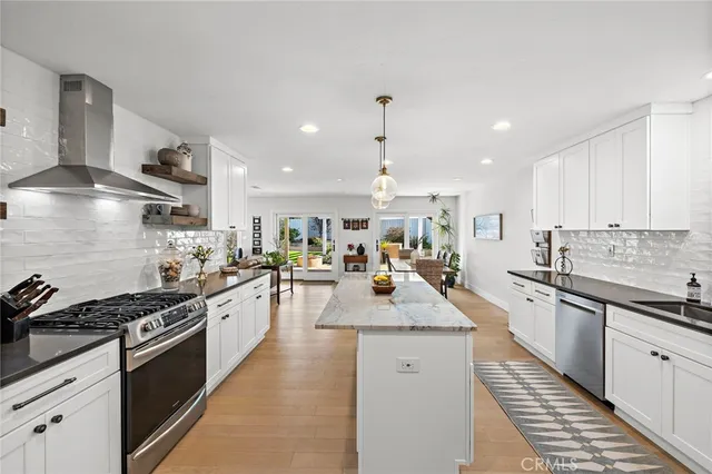 a large kitchen with stainless steel appliances granite countertop a lot of counter space and wooden floors