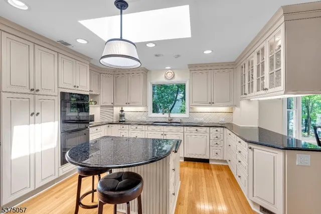 a kitchen with stainless steel appliances granite countertop a sink a stove a refrigerator cabinets and a window