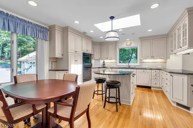 a kitchen with stainless steel appliances granite countertop a stove a kitchen island a stove a table and chairs with wooden floor