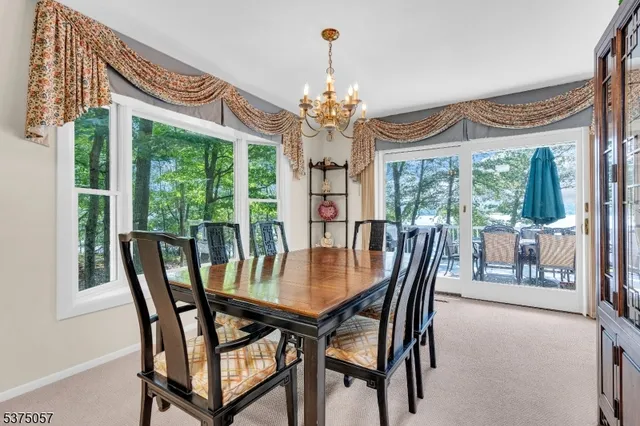 a view of a dining room with furniture a chandelier and large windows