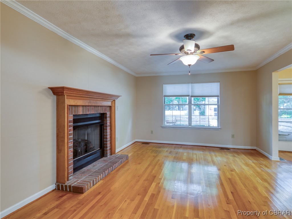 Unfurnished living room featuring a fireplace, a wealth of natural light, and light hardwood / wood-style floors
