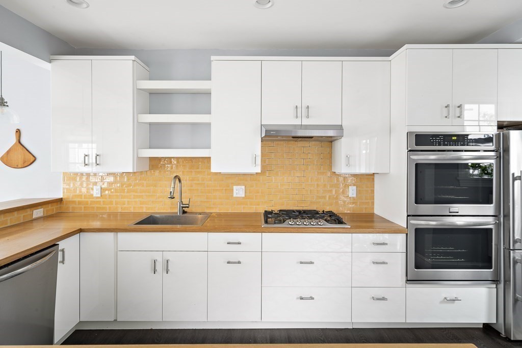10 Spring Hill Terrace Somerville, MA 02143 - Photo 4 of 20 a kitchen with granite countertop white cabinets and stainless steel appliances