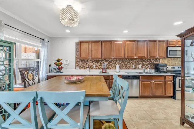 a kitchen with stainless steel appliances granite countertop a stove a sink a dining table and chairs