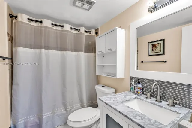 a bathroom with a granite countertop sink toilet and shower