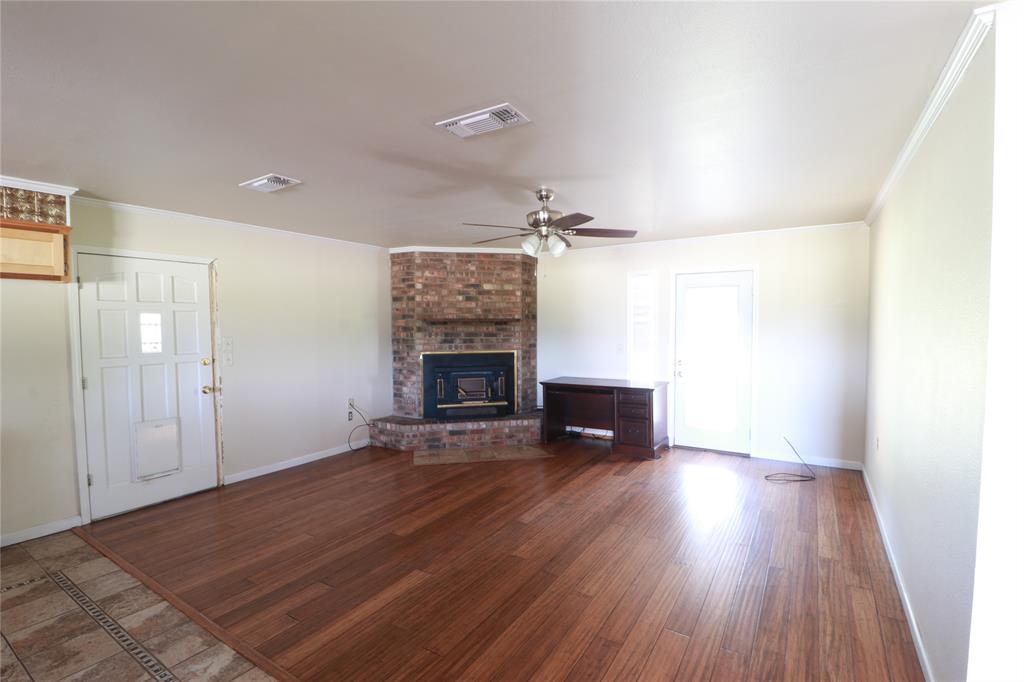 212 Palmer Drive Comanche, TX 76442 - Photo 15 of 40 an empty room with wooden floor fireplace and chandelier