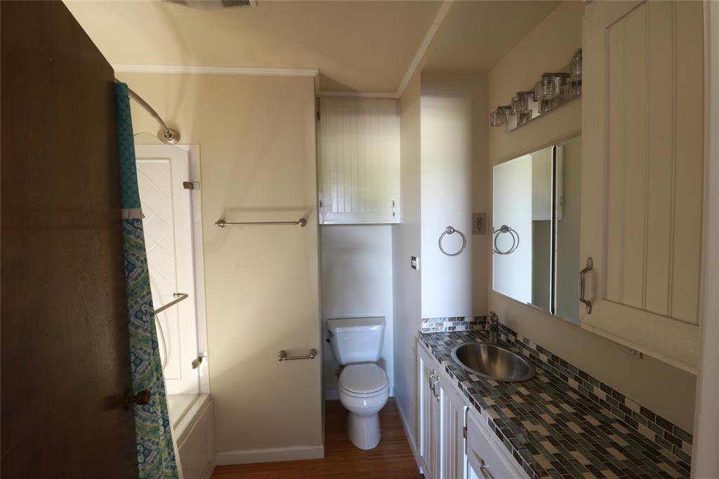 212 Palmer Drive Comanche, TX 76442 - Photo 18 of 40 a bathroom with a granite countertop toilet a sink and a mirror