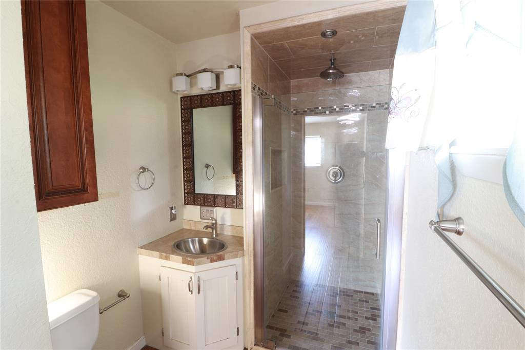 212 Palmer Drive Comanche, TX 76442 - Photo 24 of 40 a bathroom with a granite countertop sink a toilet and shower