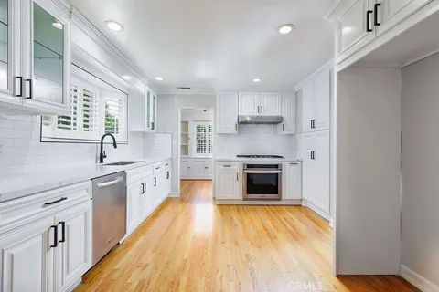 a large kitchen with stainless steel appliances granite countertop a lot of counter space and wooden floors