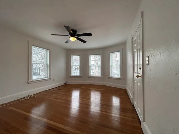 a view of empty room with wooden floor and fan