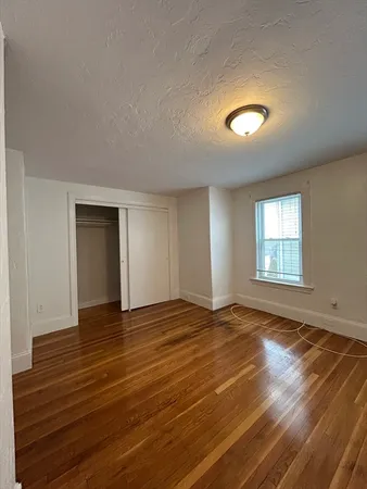 a view of an empty room with window and wooden floor
