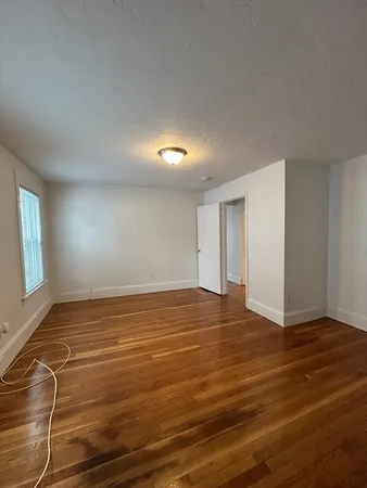 a view of an empty room with window and wooden floor