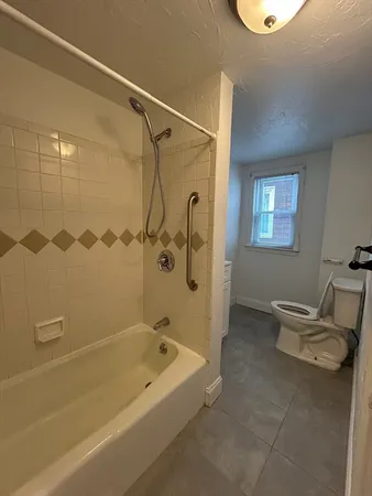 a bathroom with a tub a toilet and a shower