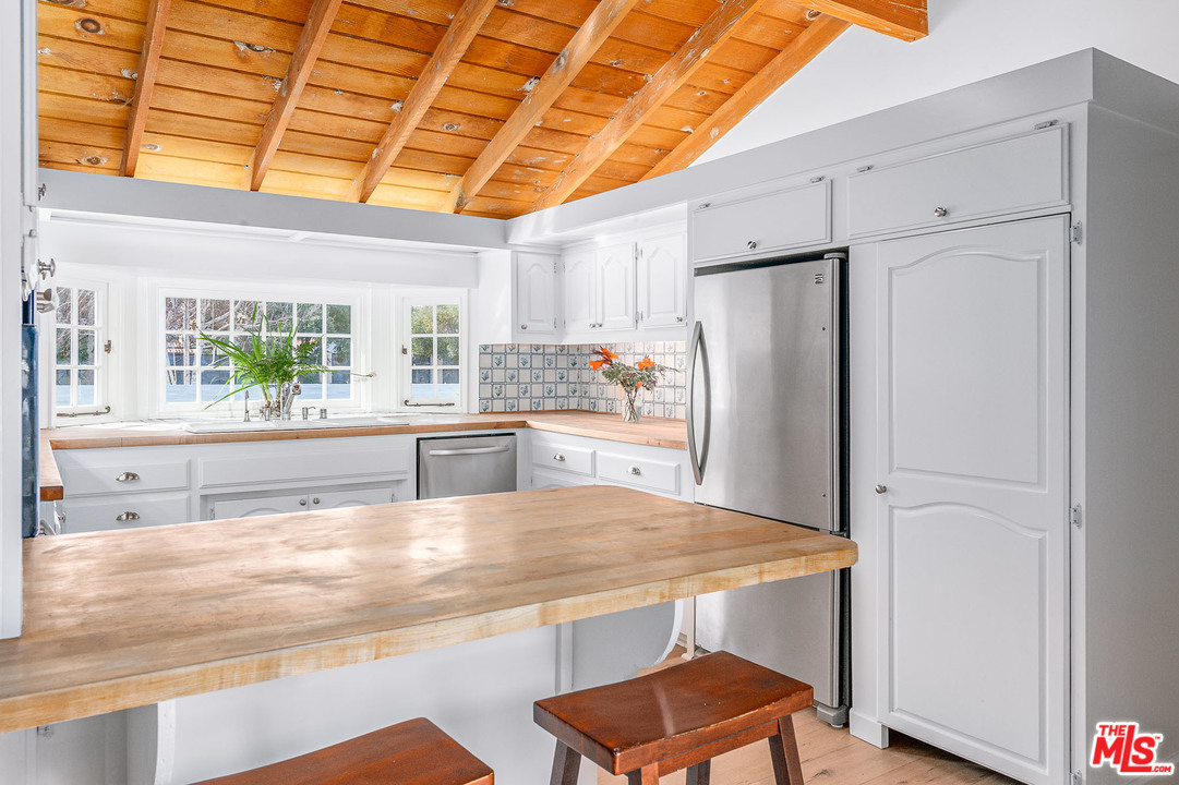 7016 Dume Drive Malibu, CA 90265 - Photo 7 of 24 a kitchen with stainless steel appliances granite countertop a refrigerator and a stove
