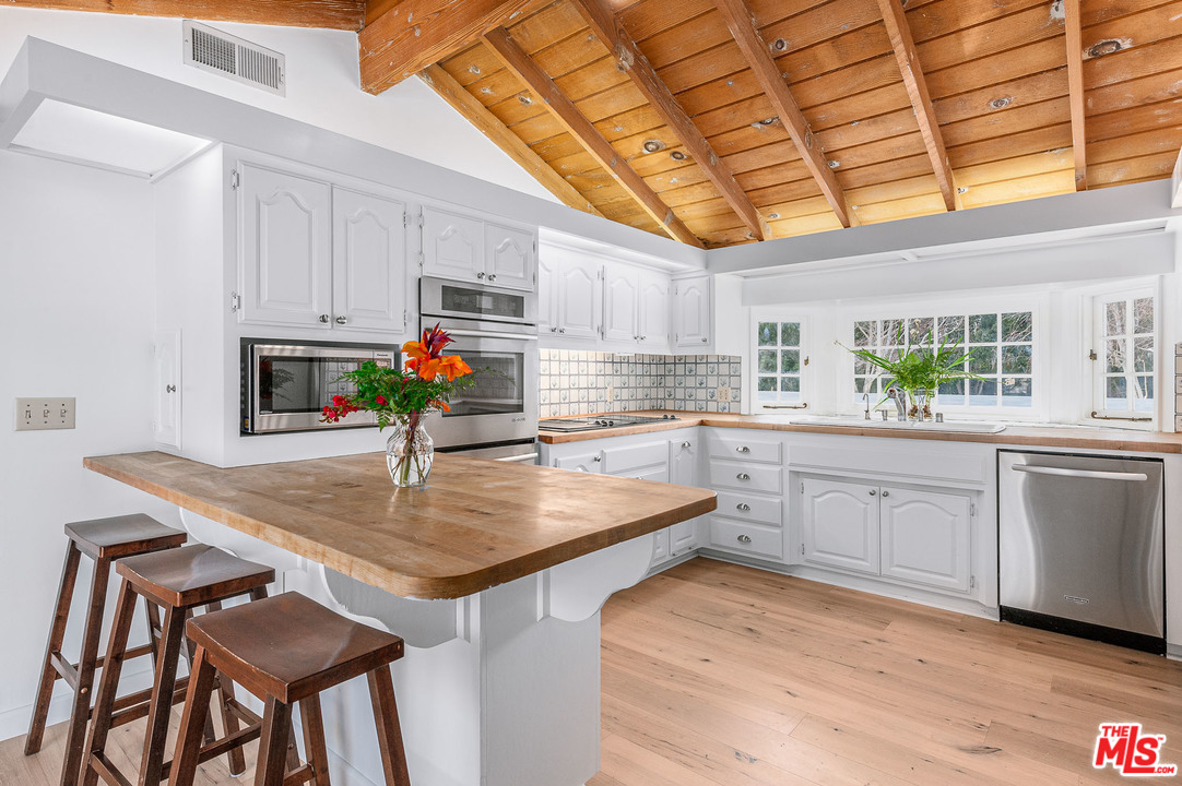 7016 Dume Drive Malibu, CA 90265 - Photo 8 of 24 a kitchen with stainless steel appliances granite countertop a kitchen island a stove a sink dishwasher and microwave