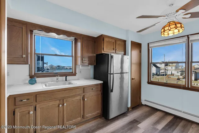 a kitchen with stainless steel appliances granite countertop a refrigerator a oven a sink and a refrigerator with wooden floor