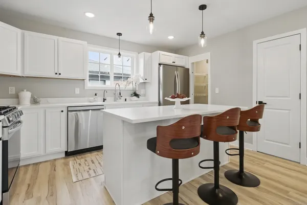 a kitchen with stainless steel appliances kitchen island granite countertop a stove a sink and a refrigerator with wooden floor