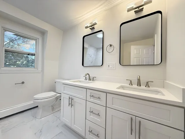 a bathroom with 2 toilet sink and a mirror