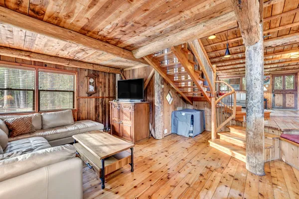 a bedroom with a bed and dresser with wooden floor