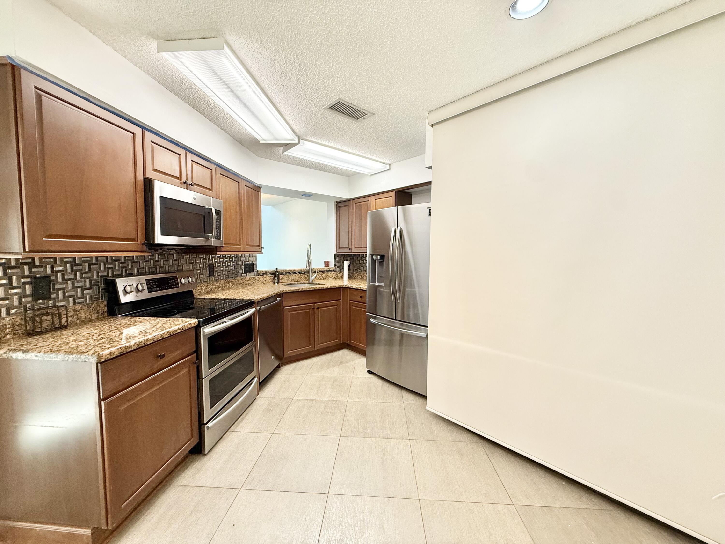 9190 Boca Gardens Parkway, Unit B Boca Raton, FL 33496 - Photo 5 of 35 a kitchen with granite countertop a refrigerator and a stove top oven
