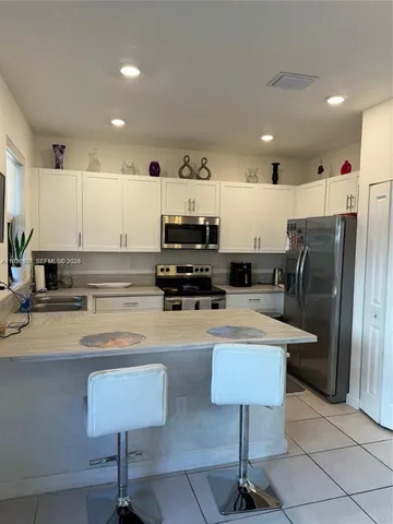 a kitchen with stainless steel appliances granite countertop a sink a stove a refrigerator a microwave cabinets and chairs