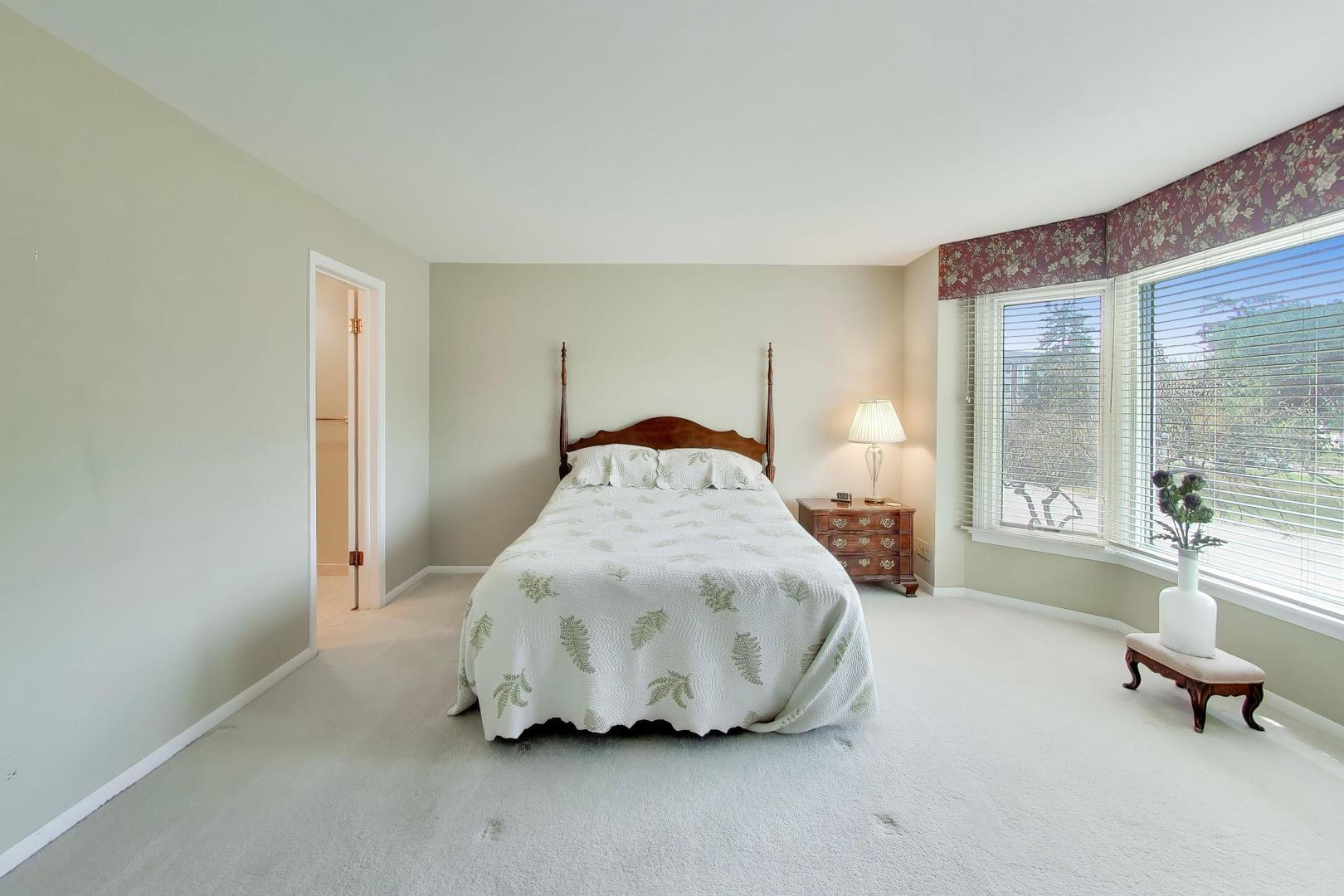 400 Ascot Drive, Unit 1M Park Ridge, IL 60068 - Photo 19 of 37 a spacious bedroom with a bed and glass door