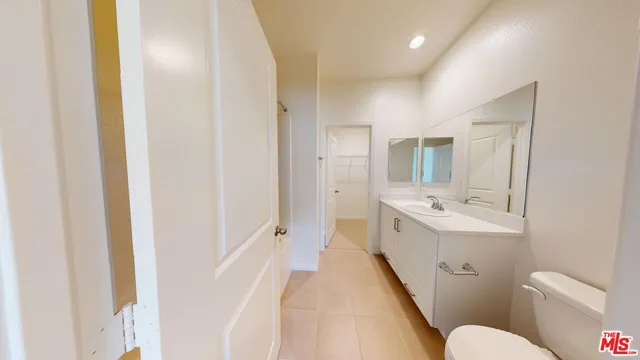 a bathroom with a double vanity sink and mirror with toilet