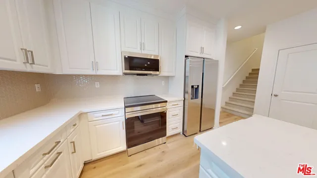 a kitchen with stainless steel appliances white cabinets and wooden floors