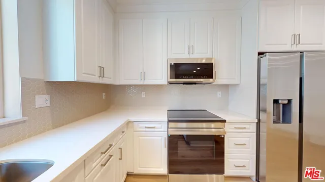 a kitchen with stainless steel appliances granite countertop a refrigerator stove and white cabinets