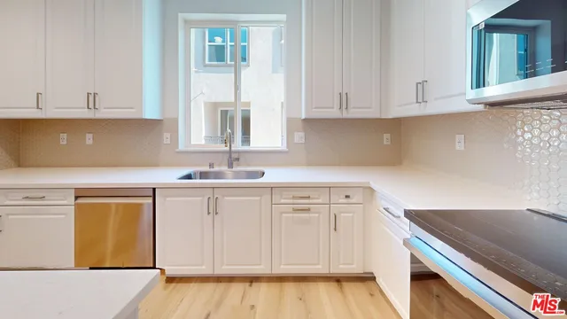 a kitchen with white cabinets and sink