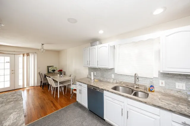 a kitchen with a sink white cabinets and wooden floor