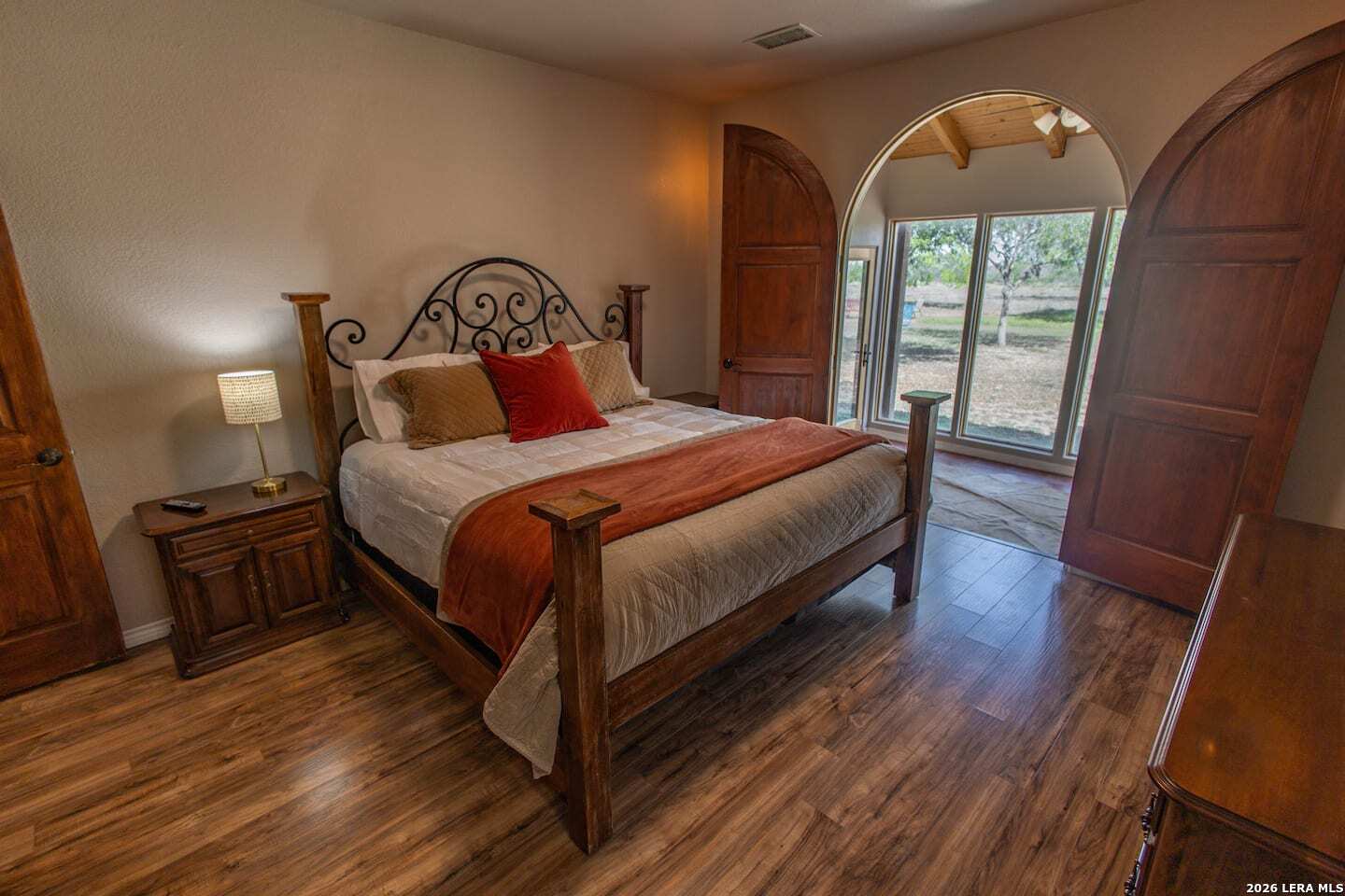 5499 Agape Road Uvalde, TX 78801 - Photo 32 of 54 a bedroom with a bed a mirror on dresser and a wooden floor
