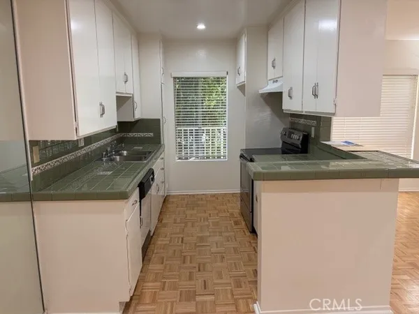 a kitchen with granite countertop a sink a stove and cabinets