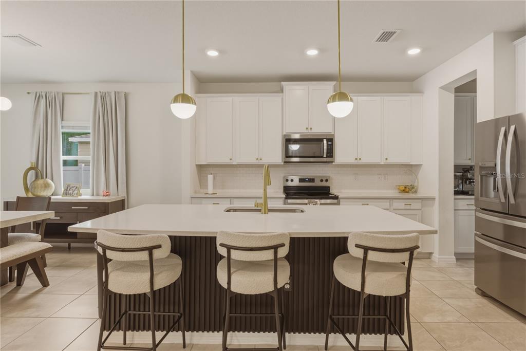 17664 Northwest 173rd Road Alachua, FL 32615 - Photo 5 of 31 a kitchen with a dining table chairs refrigerator and microwave