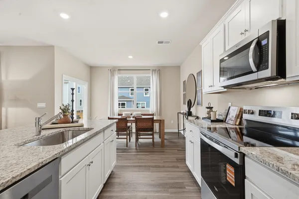 a kitchen with stainless steel appliances granite countertop a sink dishwasher stove and microwave with wooden floor