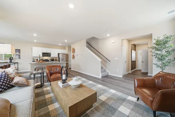 a living room with furniture kitchen view and a wooden floor