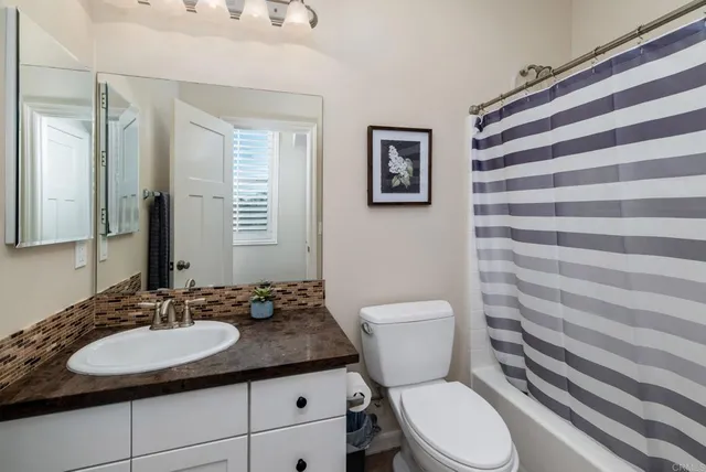 a bathroom with a granite countertop toilet sink and mirror