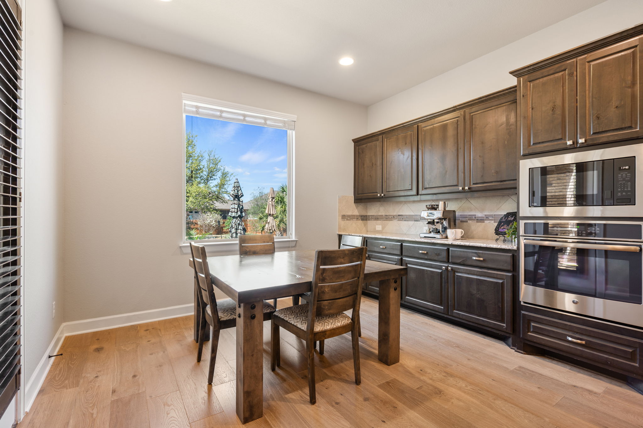 4118 Capora Way Round Rock, TX 78681 - Photo 11 of 39 a kitchen with stainless steel appliances granite countertop a stove a refrigerator a sink a dining table and chairs with wooden floor