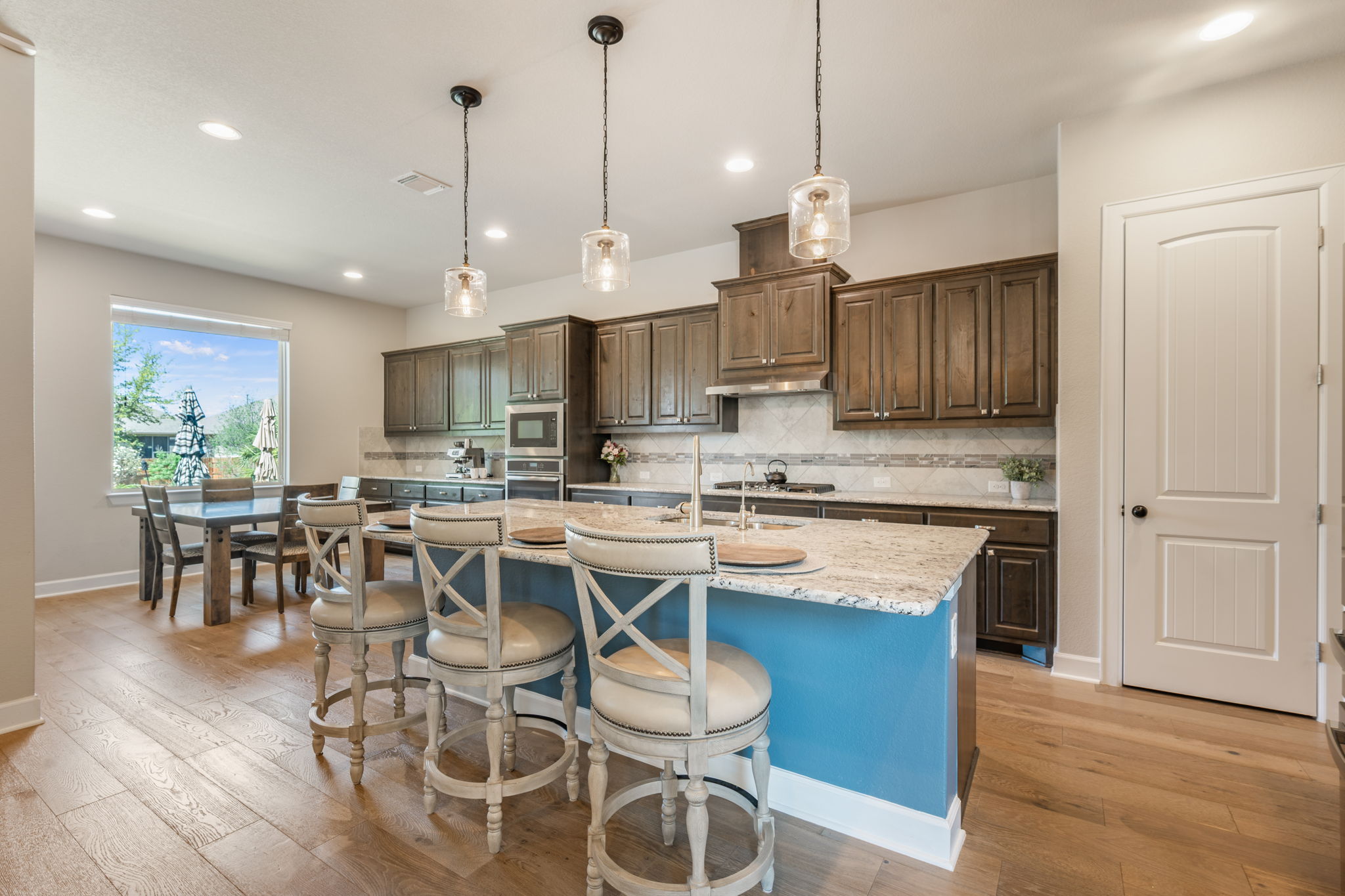 4118 Capora Way Round Rock, TX 78681 - Photo 8 of 39 a kitchen with stainless steel appliances granite countertop a stove a refrigerator a kitchen island a dining table and chairs with wooden floor