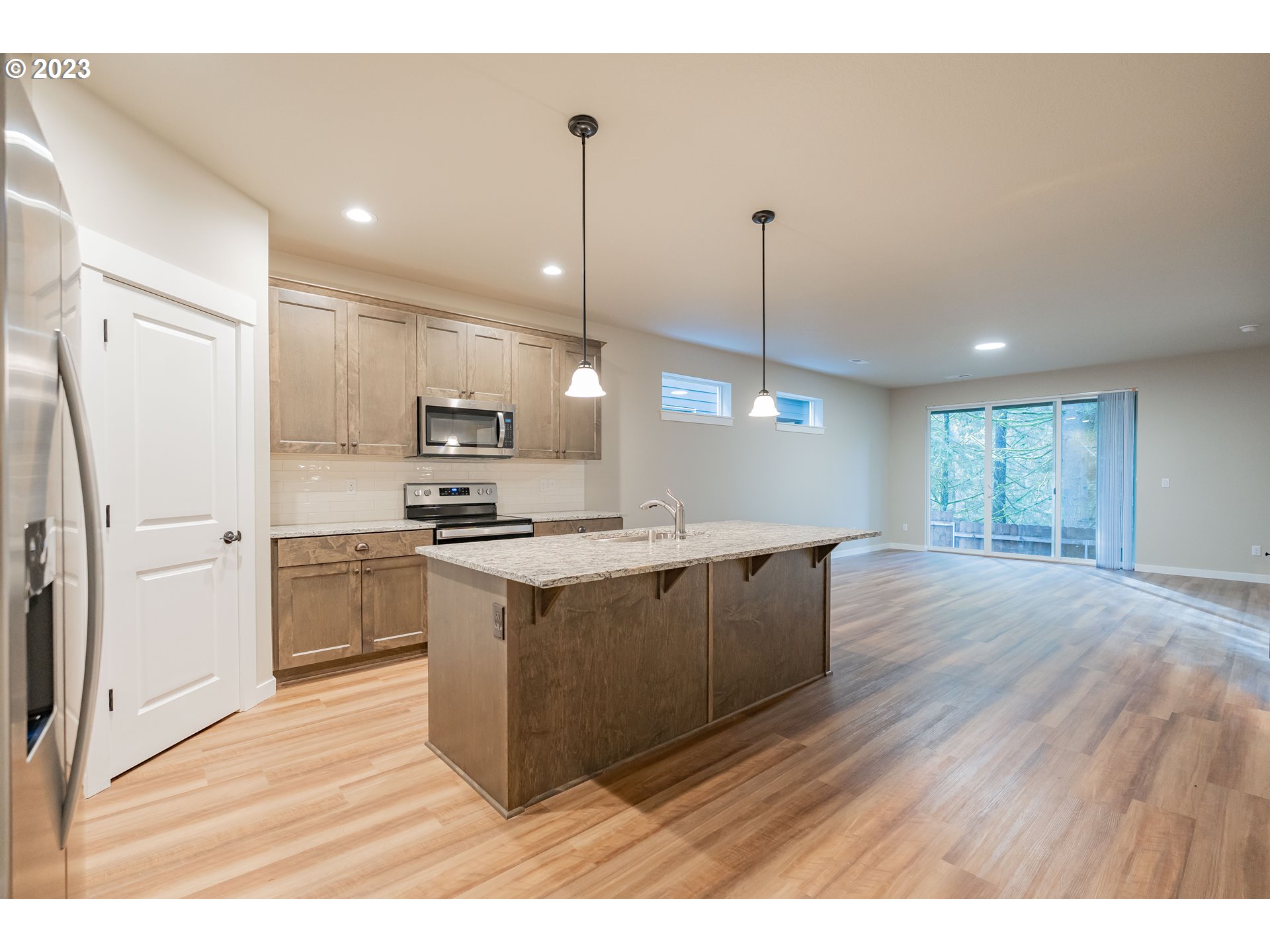 7103 South 13th Street Ridgefield, WA 98642 - Photo 2 of 31 a kitchen with stainless steel appliances granite countertop a refrigerator a sink dishwasher a stove and white countertops with wooden floor