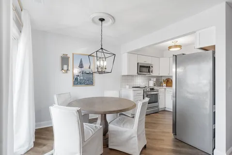 a kitchen with stainless steel appliances a dining table chairs refrigerator and microwave