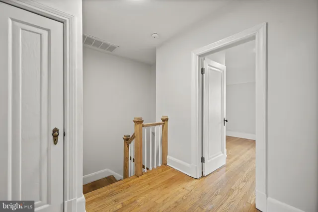 a view of a hallway with a room and wooden floor