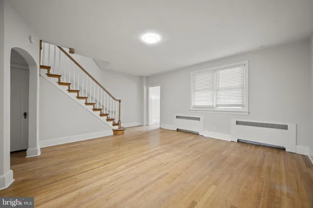 a view of an empty room with wooden floor and stairs
