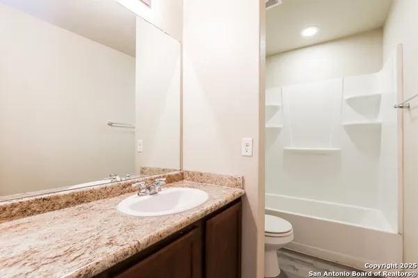 a bathroom with a granite countertop sink toilet and shower