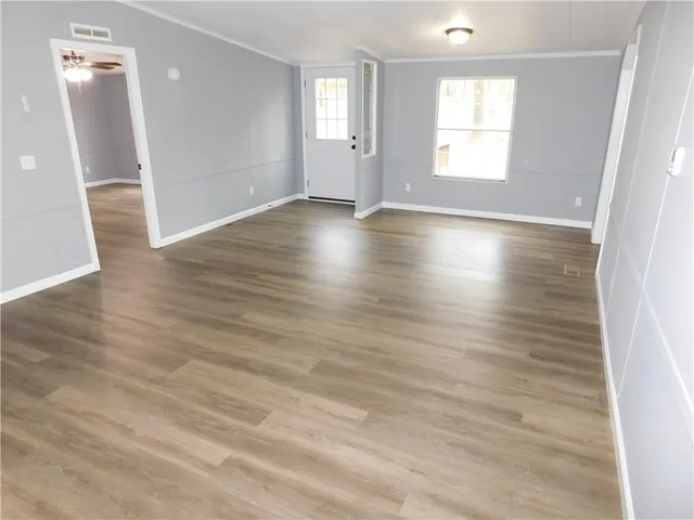 an empty room with wooden floor and windows
