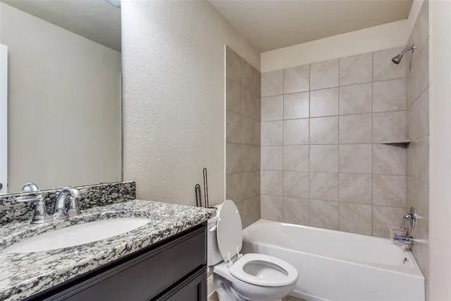 a bathroom with a granite countertop bathtub sink vanity mirror and toilet