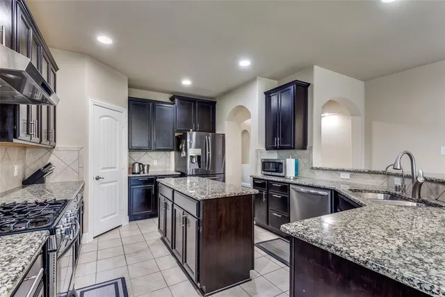 a kitchen with stainless steel appliances granite countertop sink stove top oven and refrigerator