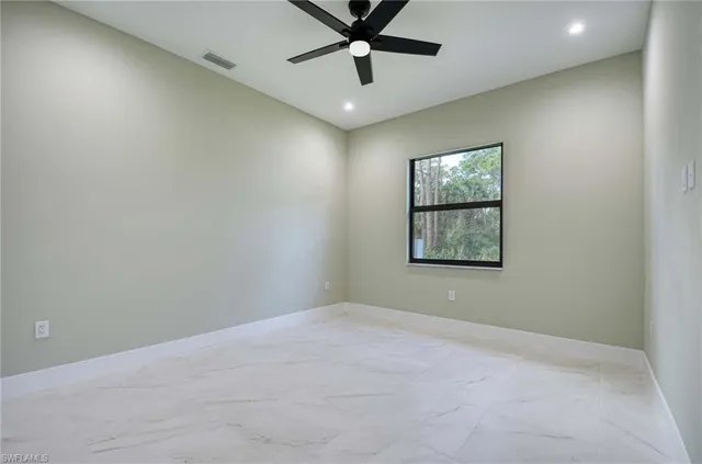 an empty room with windows and fan