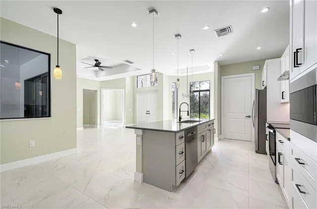 a large kitchen with stainless steel appliances a large counter top a stove a sink and a refrigerator