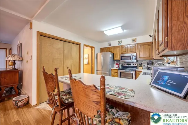 a large kitchen with stainless steel appliances wooden floor dining table and chairs