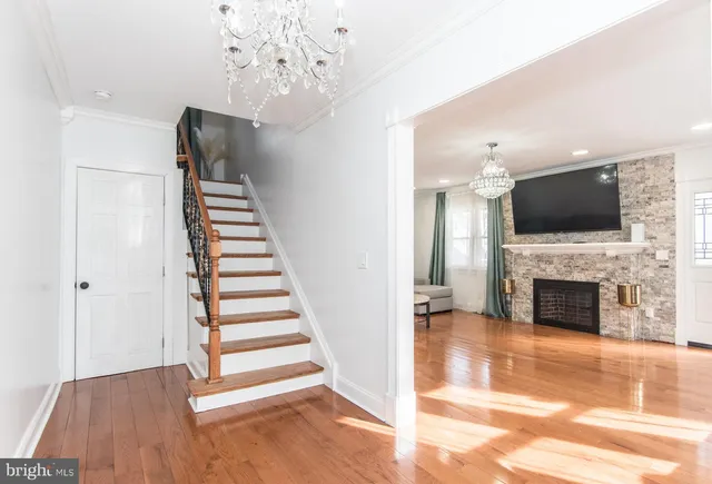 a view of a livingroom with wooden floor a fireplace a clock and stairs